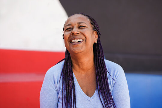 Happy african senior woman smiling in front of camera with colorful background - Joyful elderly person and urban lifestyle concept