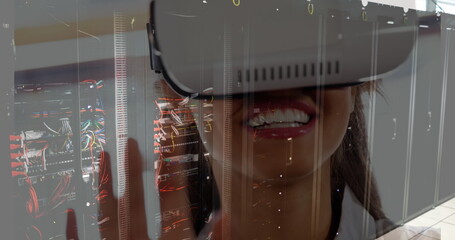Image of server room over biracial woman using vr headset