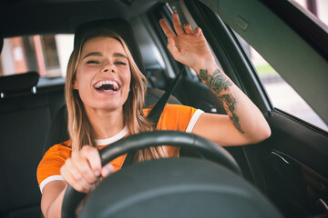 Happy young woman enjoying a car ride with a cheerful expression during daylight in a casual urban...