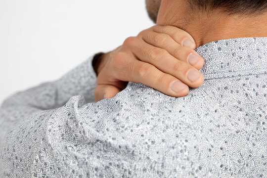 Close-up of man's hand on neck, showcasing neck pain concept. Gray patterned shirt texture visible.  Illustrates discomfort, tension, or stress. - Powered by Adobe