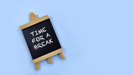 Mini blackboard with word time for a break on blue background.  © OrangRobot