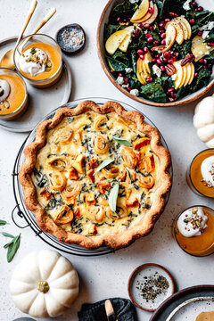 Fall holiday meal with quiche and sald and pumpkins