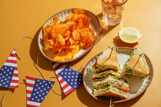 club sandwich served on a wooden cutting board. The sandwich is layered with crispy toasted bread, fresh lettuce, ripe tomatoes, slices of ham, and cheese
