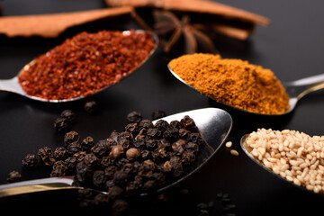 Close up and soft focus spices, sesame, pepper, turmeric, cayenne peper on black background.