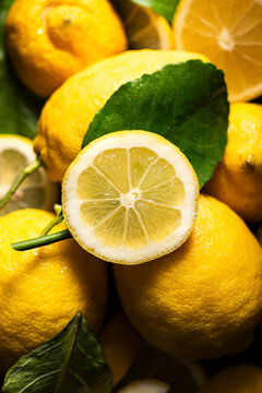 Closeup of sliced lemon amongst other lemons
