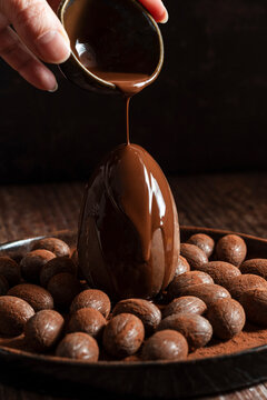 Hand Pouring Chocolate Sauce over Easter Egg
