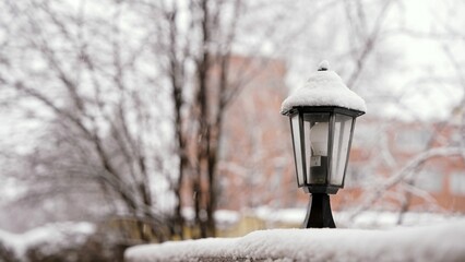 Gentle snowfall blanketing lamp post, accumulating softly on urban street during tranquil winter scene, creating serene streetscape with delicate white precipitation © Ruslan