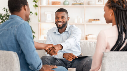 Marriage Counseling. Thankful Black Couple And Marital Therapist Shaking Hands After Successful Meeting In Office, Selective Focus