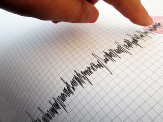Seismograph and earthquake. A hand pointing at a seismograph recording the seismic activity of an earthquake