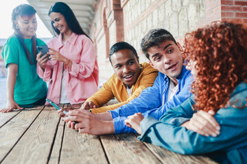Young friends using mobile phone. Diverse students having fun with smartphones outside school university. Youth culture concept