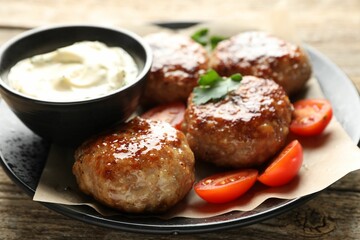 Delicious patties, parsley, tomatoes and sauce on wooden table, closeup