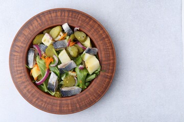 Delicious salad with herring and vegetables on light grey table, top view. Space for text