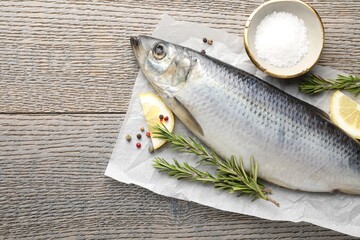 Salted herring and spices on wooden table, flat lay. Space for text