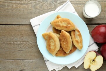 Delicious fried pyrizhky (stuffed pies) with apples and milk on wooden table, flat lay. Space for text