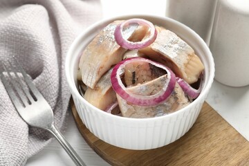 Pieces of delicious herring with onions on white table, closeup