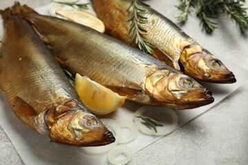 Smoked herrings, onion, rosemary and lemon on light grey table, closeup