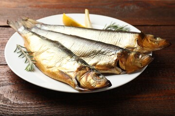 Smoked herrings, rosemary and lemon on wooden table, closeup