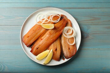 Smoked herrings, lemon and onion on light blue wooden table, top view