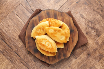 Delicious fried pyrizhky (stuffed pies) on wooden table, top view