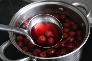 Making compot of cherries. Simmering fruits in pot on stove, closeup