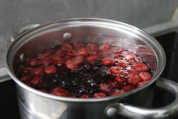 Making compot of cherries. Simmering fruits in pot on stove, closeup