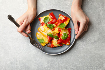 Woman eating delicious ravioli at grey table, top view