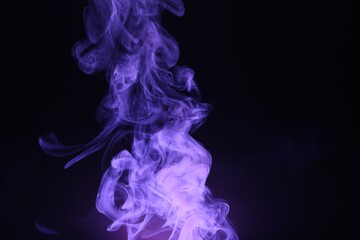 Obraz premium Beautiful smoke in purple light on dark background, space for text