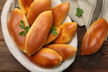Tasty baked patties and parsley on wooden table, top view