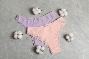 Women's underwear. Beautiful panties and cotton flowers on gray marble background, flat lay