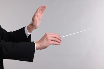 Conductor with baton on light grey background, closeup