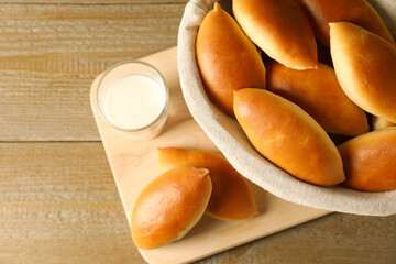 Tasty baked patties and milk on wooden table, top view