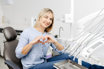 Patient showing heart shape with hands sitting in dentist chair