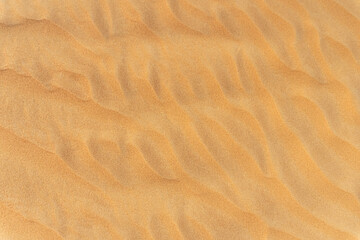 Close-up  background brown sand wave with rippled dunes. Top view. Space for text. Sand summer texture.