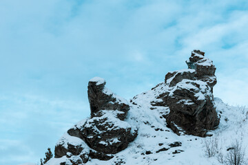 A rocky mountain covered in snow with a blue sky in the background