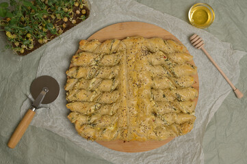 Top view sprinkled with sesame seeds baked twisted dough strips. Microgreen, cutter and egg on kitchen table. Home cooking baking puffs