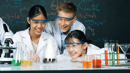 Girl looking at beaker while doing experiment at blackboard with chemistry theory in STEM class....