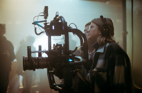A female director at work on the set. The director works with a band or with a speaker during the filming of a movie, commercial, or television series. The crew, equipment, and crew. 
