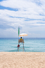 A lone lifeguard tower stands vigilant on a tranquil beach, symbolizing safety and watchfulness