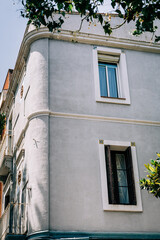 A detailed corner view of a classic urban building showcasing traditional architectural design elements under a clear blue sky, representing urban lifestyle and real estate