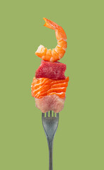 Various protein rich foods, including shrimp, beef, salmon, and chicken, stacked on a fork against...