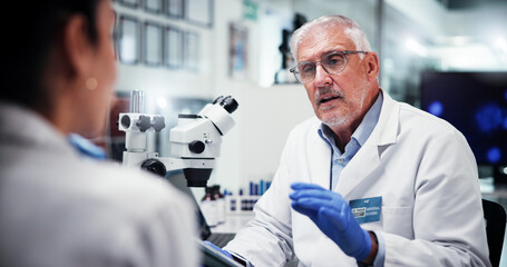 Mature, scientist and man with colleague in laboratory, feedback or review with tablet for medical...
