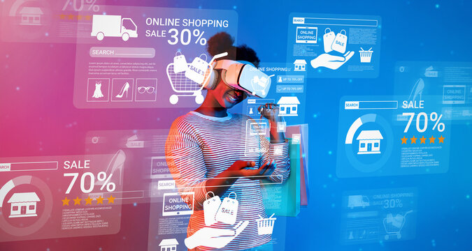 Happy teenager wearing VR glasses and looking online shopping screen. Smart african girl using augmented reality technology at blue and pink background. Technology innovation concept. Ingenuity.