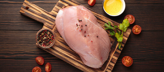 Raw turkey fillet seasoned with peppercorns on a wooden cutting board, garnished with fresh parsley...