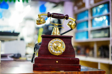 A retro rotary dial telephone adorned with intricate golden accents and wooden housing, positioned...