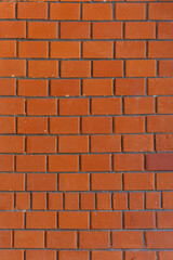 A brick wall with a red color. The wall is made of bricks. The bricks are arranged in a pattern