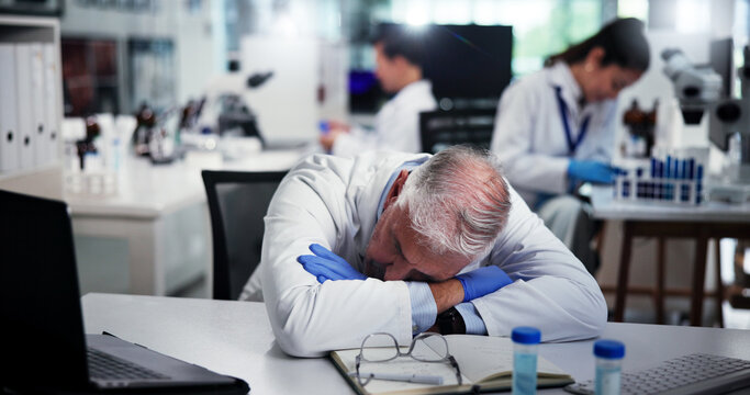Tired, scientist and man sleeping in laboratory for burnout, deadline and exhausted with research. Medical science, fatigue and mature professional with stress, overworked and rest for low energy - Powered by Adobe