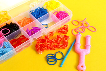  The transparent container stands on a yellow background with bright multi-colored rubber bands for...