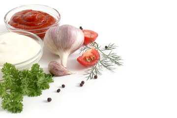 On a white background there are two cups with mayonnaise and ketchup with vegetables.