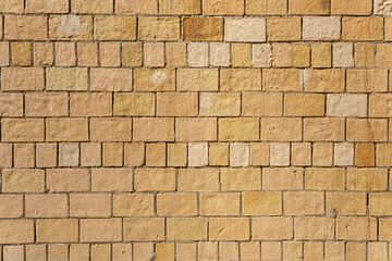 The brick wall is brown and yellow. The bricks are laid unevenly.