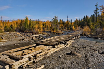 Russia. The Altai Mountains. A dilapidated wooden bridge over the Aktra River, which all-terrain vehicles drive around along the stone riverbed on the way to the ancient glacier of the same name.